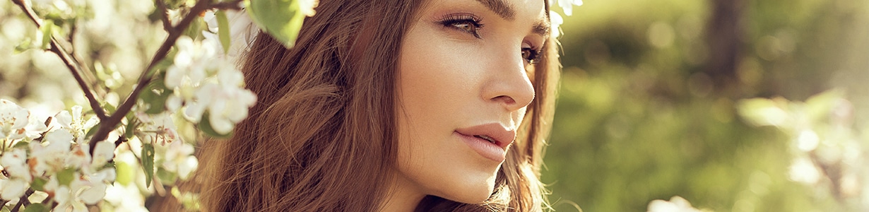 woman peering through flowers with mystical look