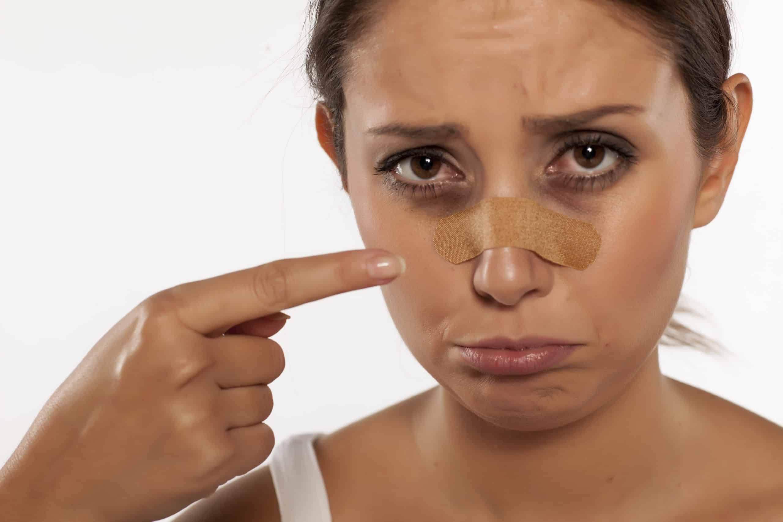woman with band aid on nose and pouting face with white background