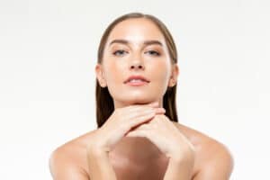 A woman posing with her hands under her chin, showing clear skin from Morpheus8