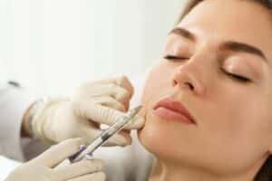 Woman's face, with eyes peacefully closed, as doctor administers RHA fillers in her smile lines