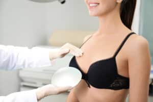 Woman smiling and looking at implants with plastic surgeon for breast lift with augmentation