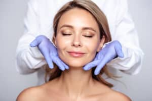 Woman with eyes closed and surgeon's hands showing fresh skin from Halo laser in Houston