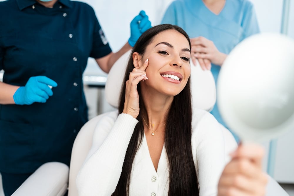 Woman looking in the mirror during a consultation to determine if she should get a facelift in Houston