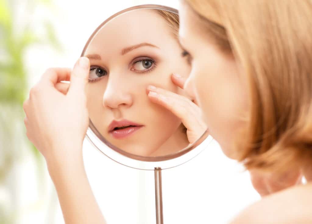 Woman looking in the mirror after a facelift in West Houston, TX
